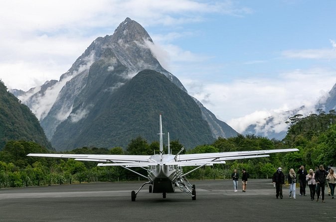 A small plane on the airstrip below a sharp peak