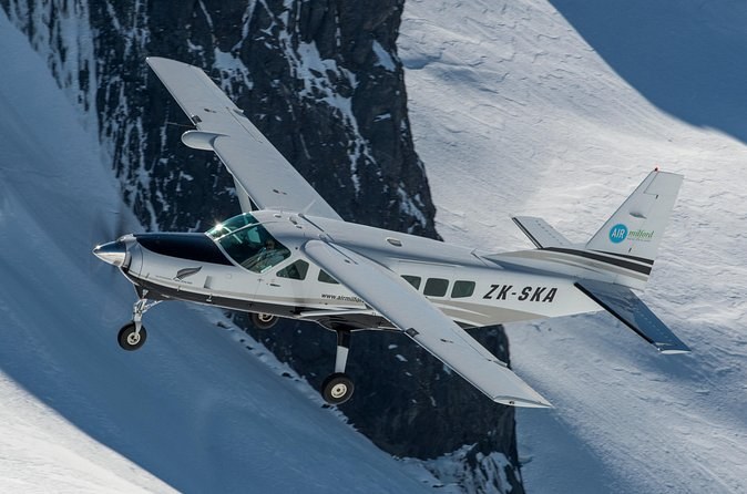 A small plane flying over snowfields